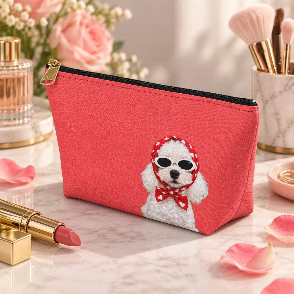 Red makeup pouch with a white Poodle in sunglasses and a red scarf beside flowers and perfume