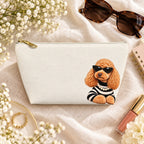 Cream makeup pouch with an apricot Poodle in sunglasses and a striped top flat lay with sunglasses