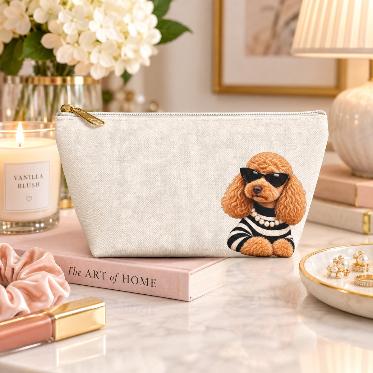 Cream makeup pouch with an apricot Poodle in sunglasses and a striped top on books beside flowers
